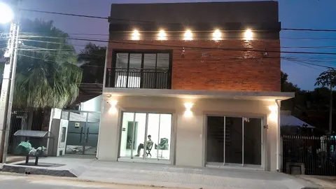 Fachada de ladrillo de un local de dos plantas con spots y apliques encendidos al anochecer